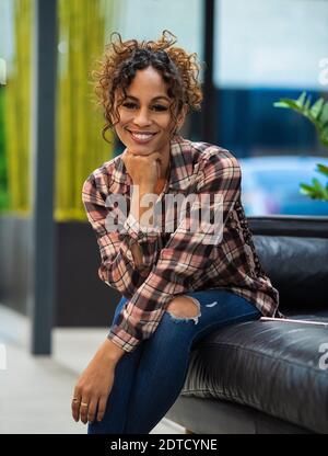 Ritratto di donna sorridente seduta sul divano in ufficio Foto Stock