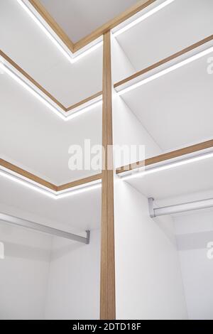 Elegante scaffale bianco con illuminazione a LED. Scaffalatura di pannelli laminati con bordi e facce di cassetti in fogli di compensato di quercia impiallacciata in camino cl Foto Stock