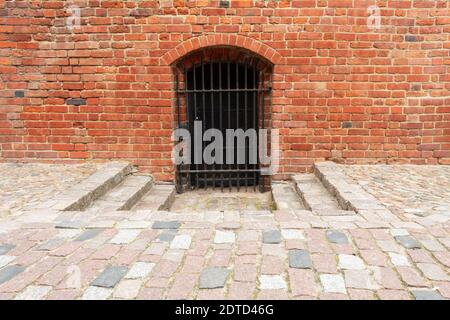 Porta nel muro di un vecchio castello. Reticolo in un muro di argilla rossa Foto Stock