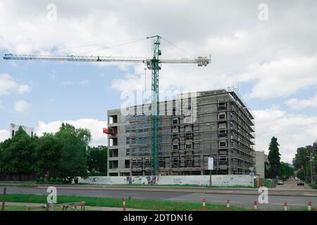 Una casa è in costruzione con una gru a torre. Costruzione di un edificio residenziale. Impalcature intorno alla casa Foto Stock