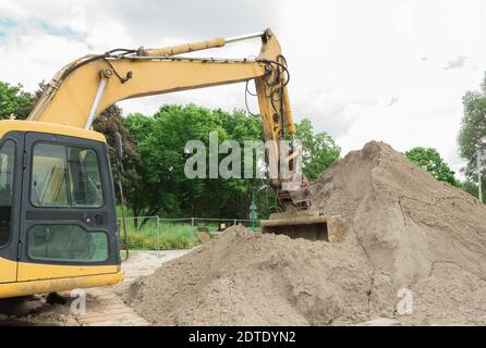 Un escavatore sta guadagnando terreno in una benna. Escavatore arancione e vecchio con pala Foto Stock