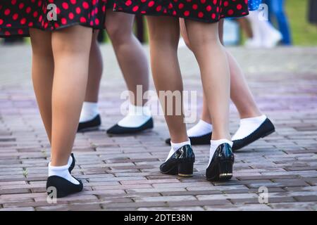 Giovani donne che indossano abiti a pois vintage che ballano nel parco cittadino, vista ravvicinata delle stesse scarpe da ballo nere e calzini bianchi, swing jazz retrò femminile Foto Stock