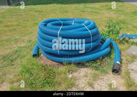 Tubo corrugato attorcigliato in un rotolo. Il tubo corrugato blu si trova a terra Foto Stock