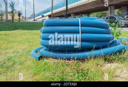 Tubo corrugato attorcigliato in un rotolo. Il tubo corrugato blu si trova a terra Foto Stock