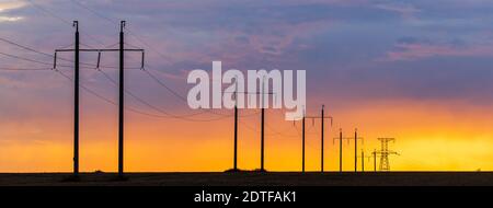 Paesaggio rurale con linea ad alta tensione sul tramonto. Spettacolare vista del cielo Foto Stock