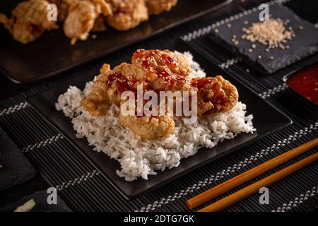 Gamberetti tempura, serviti con riso su un piatto nero. Cibo cinese. Sushi Foto Stock
