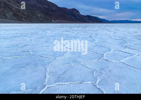 Badwater Basin all'alba, Death Valley, California. Montagne in lontananza. I depositi di cristallo formano forme esagonali Foto Stock