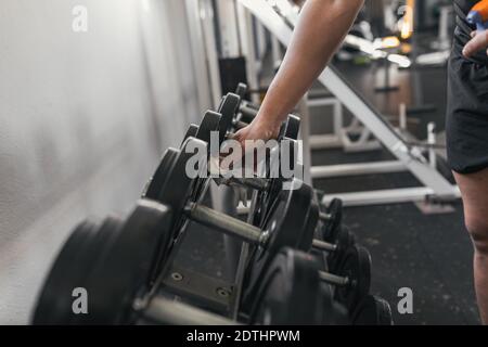 Primo piano dell'atleta che indossa guanti protettivi e disinfetta i pesi delle mani presso il centro benessere. Foto Stock