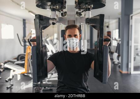 Giovane uomo che usa una macchina da palestra con maschera. Concetto di sport e salute. Foto Stock