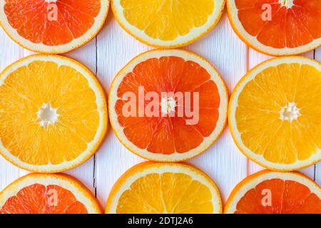 Arance a fette accatastate in file su un tavolo di legno bianco Foto Stock