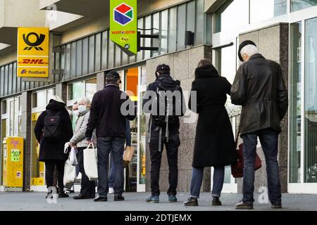 Dortmund, Germania, 18 dicembre 2020: I clienti aspettano sul marciapiede di fronte ad una filiale di Deutsche Post/DHL a Dortmund. A causa delle limitazioni del secondo blocco della pandemia corona, solo 3 clienti sono autorizzati a rimanere in questa filiale contemporaneamente. Foto Stock