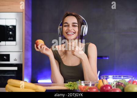 Felice giovane donna sana mangiare frutta fresca tenendo una mela in mano grinning alla macchina fotografica. Un sorriso perfetto. Foto Stock