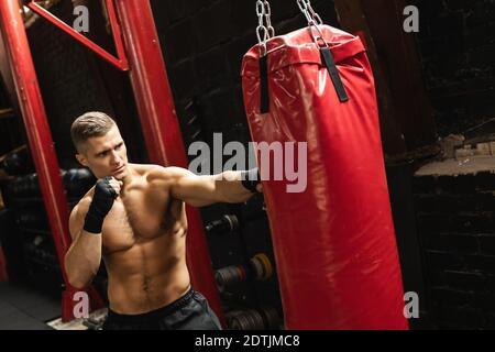 Forte giovane combattente mma e borsone rosso nel palestra Foto Stock