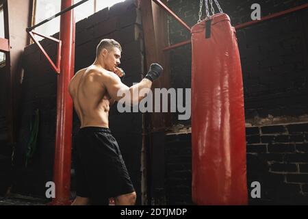 Forte giovane combattente mma e borsone rosso nel palestra Foto Stock