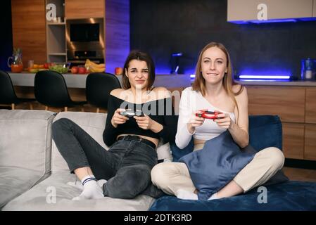 Due migliori girlfriends con una forte eccitazione giocano un interessante videogioco. Amichevole gioco di computer a casa. Foto Stock