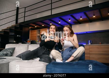 Bella migliore girlfriends hanno video giochi concorrenza a casa mentre hanno tempo di riposo. Goditi il tempo libero per trascorrere il tempo libero con gli amici. Foto Stock