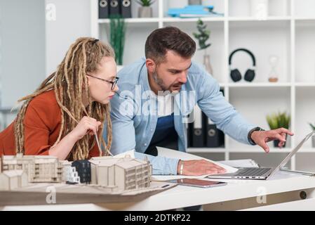 Designer creativi di alto livello, maschili e femminili, che lavorano con un mock-up di edifici futuri Foto Stock