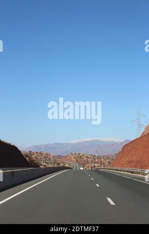 Un'immagine verticale di una strada curvilinea che attraversa un paesaggio asciutto sotto un cielo limpido Foto Stock