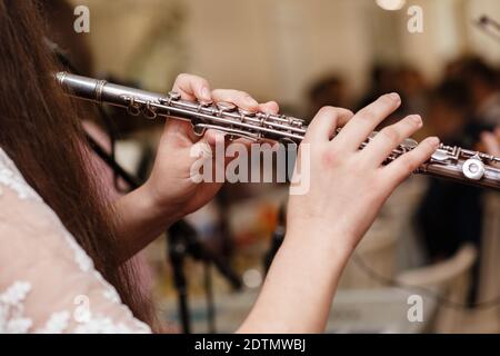 Flutista, giovane ragazza che gioca il flauto, mani, dita su tasti closeup, bambini che giocano trasversale laterale flauto, dettaglio scatto, musica classica, vento Foto Stock