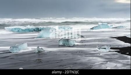 Iceberg sulla spiaggia vulcanica nera. Spiaggia dell'atlantico nord vicino alla laguna glaciale Joekulsarlon e ghiacciaio Breithamerkurjoekull nel Vatnajoeku Foto Stock