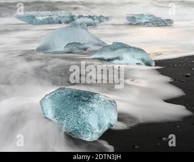 Iceberg sulla spiaggia vulcanica nera. Spiaggia dell'atlantico nord vicino alla laguna glaciale Joekulsarlon e ghiacciaio Breithamerkurjoekull nel Vatnajoeku Foto Stock