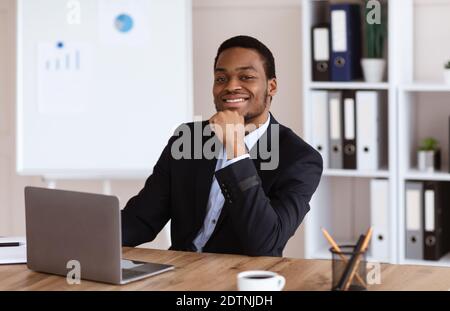 Uomo d'affari afro-americano di successo seduto nel suo ufficio Foto Stock