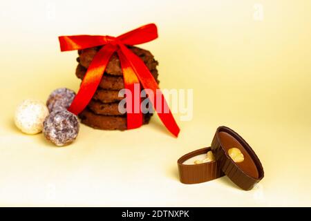 Biscotti al cioccolato e cioccolatini su sfondo giallo. Foto Stock