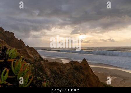 Molte bizzarre dune di sabbia erose sull'Oceano Atlantico con onde che si infrangono al tramonto Foto Stock