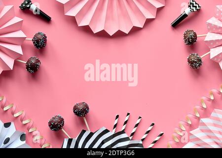 Cornice decorativa con spazio di copia. I papi della torta yummy sono ricoperti di cioccolato e glassa di zucchero colorata. Piano monocromatico creativo su carta rosa decorata Foto Stock