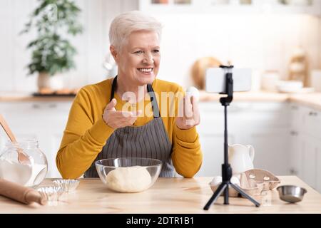 Anziana donna blogger cibo registrazione della sua cucina da in cucina Foto Stock