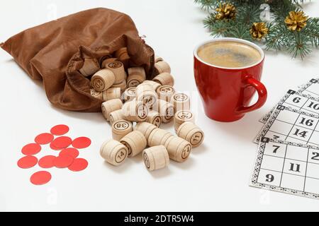 Lotto di gioco da tavolo. Botti di legno lotto con una borsa marrone, carte da gioco, patatine rosse e una tazza di caffè, rami di abete di Natale sullo sfondo Foto Stock