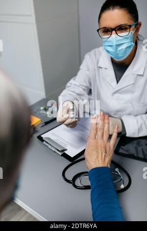Paziente femminile che rifiuta il vaccino del coronavirus offerto dal medico Foto Stock