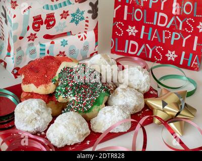 Biscotti di Natale assortiti su un tagliere rosso con festa confezioni e nastro Foto Stock