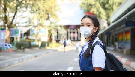 Torna a scuola. ragazza asiatica bambino indossare maschera viso con zaino andare a scuola .Covid-19 coronavirus pandemic.New stile di vita normale.concetto di educazione Foto Stock