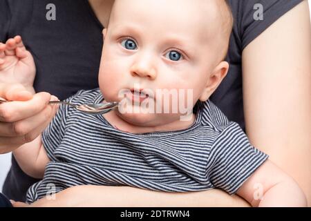 Madre che alimenta bambino ragazzo con vitamina o medicina liquida usando cucchiaio Foto Stock