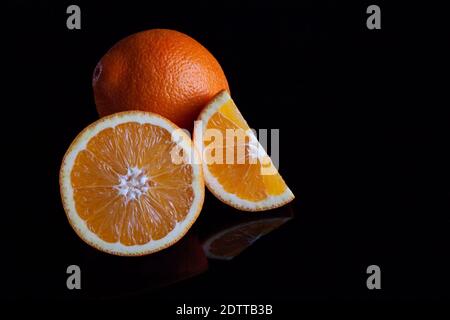 Immagine di frutta arancione su sfondo nero riflettente Foto Stock