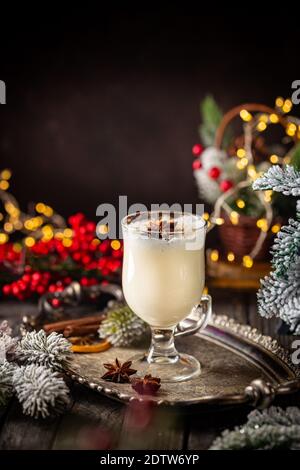 Tradizionale inverno eggnog in una tazza di vetro con latte, rum e cannella, decorazioni natalizie Foto Stock