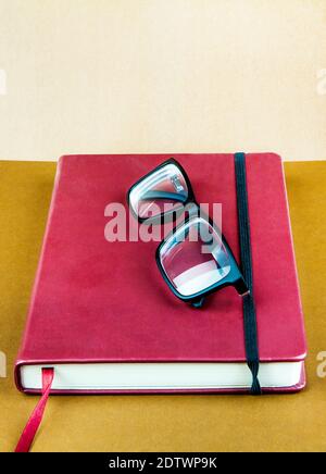 Libro rosso con un bicchiere sullo sfondo di carta marrone primo piano Foto Stock