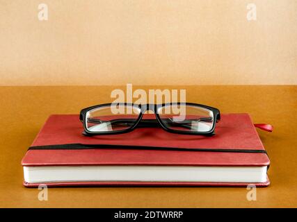 Libro rosso con un bicchiere sullo sfondo di carta marrone primo piano Foto Stock