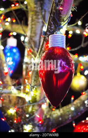 Grandi ornamenti e luci su un albero esterno, decorato per Natale. Foto Stock