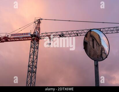 GRU DI COSTRUZIONE CON SPECCHIO PER LE AUTO, CON UN BEL CIELO OVERCAST AL TRAMONTO Foto Stock