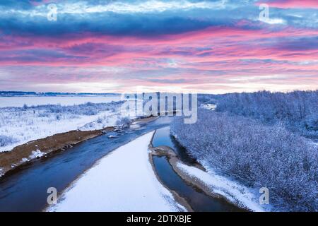 Flight through majestic river, frozen forest and frosty winter fields at sunrise time. Landscape photography Foto Stock