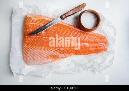 Filetto di salmone su tavola di legno con coltello e sale. Fotografia alimentare Foto Stock