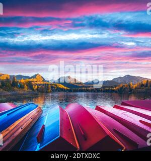 Pittoresca vista autunnale del lago Strbske pleso nel Parco Nazionale di High Tatra, Slovacchia. Fila di barche di legno rosso e alte montagne sullo sfondo. Fotografia di paesaggio Foto Stock