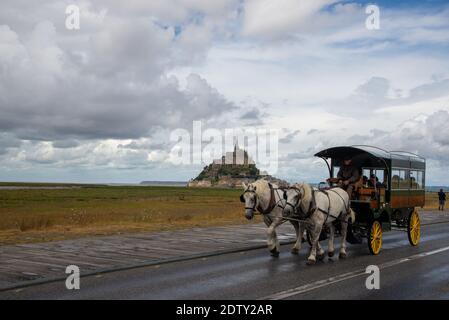 Carrello di cavalli con i visitatori a Mont St. Michel in Bretagna, Francia Foto Stock