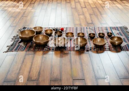 Molte bocce cantanti tibetane artigianali sul pavimento in classe yoga, concetto di terapia del suono Foto Stock