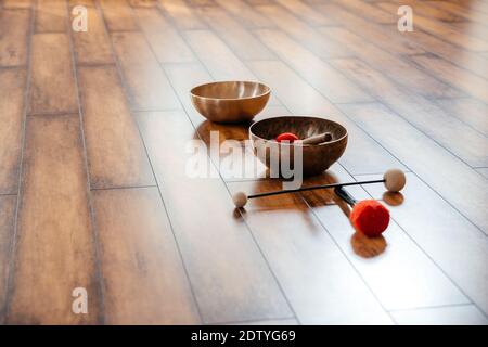 Bocce cantanti tibetane realizzate a mano sul pavimento in classe yoga, concetto di terapia del suono Foto Stock