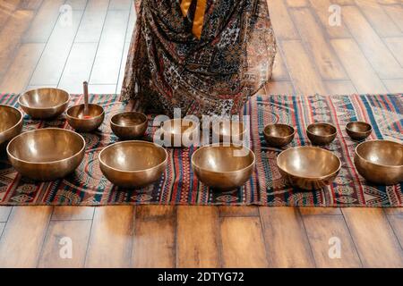 Bocce cantanti tibetane realizzate a mano sul pavimento in classe yoga, concetto di terapia del suono Foto Stock