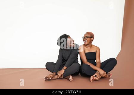 due donne nigeriane sedute e ridenti in studio Foto Stock