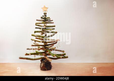 Albero di Natale rustico fatto di rami di legno grezzo decorato con luci fairy e una stella, casa sostenibile ed eco amichevole alternativa per gli holi Foto Stock